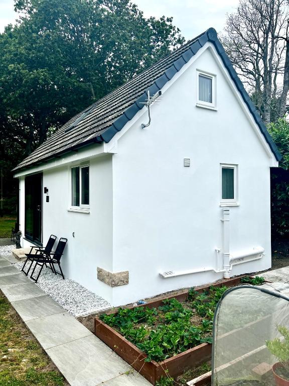 a white cottage with a black roof at Pixie Cottage in Stoborough