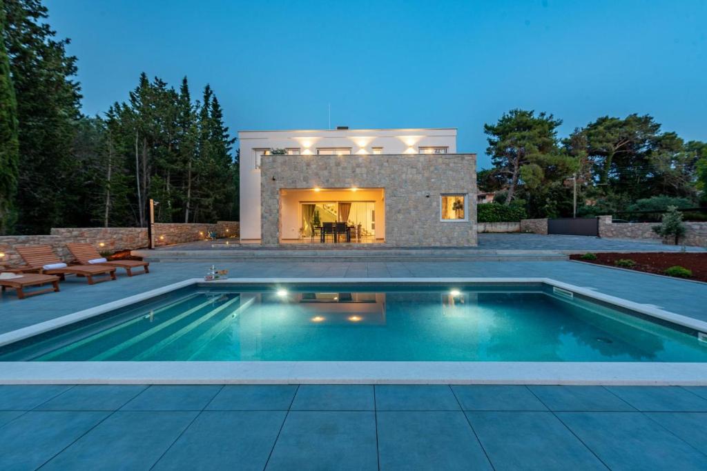 a swimming pool in front of a house at Villa Molaris Muline in Ugljan