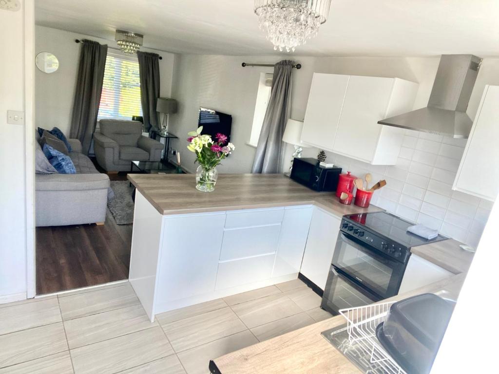 a kitchen with white cabinets and a vase of flowers on the counter at Cheerful 2-bedroom home with free parking in Roughhill