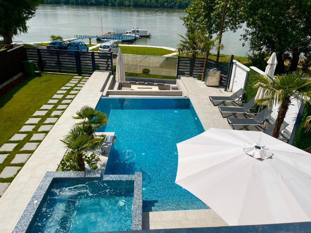 a swimming pool with an umbrella and chairs and a swimming pool at Casa Palmera in Novi Sad