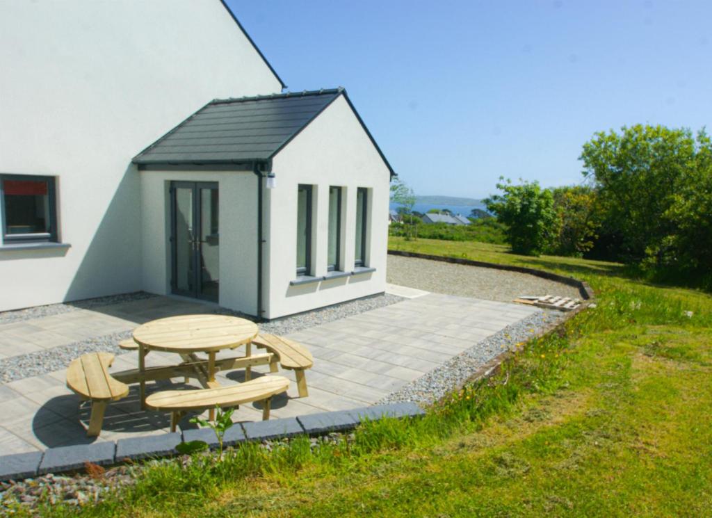 a picnic table and chairs in front of a small building at Bell View Holiday Home Sheeps Head in Bantry