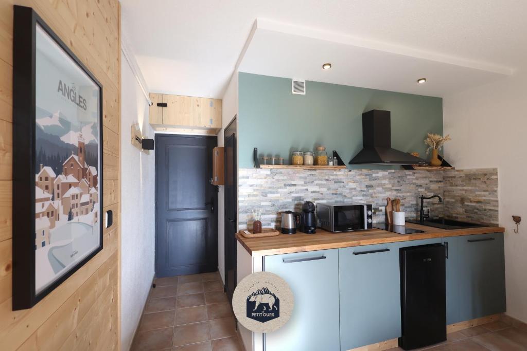 eine Küche mit blauen Schränken und einer Ziegelwand in der Unterkunft Le Petit Ours & Le Petit Cerf - Studios vue lac & montagnes in Les Angles