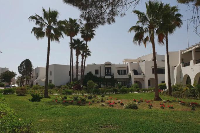 un parque con palmeras y flores frente a un edificio en Charmant Studio vue mer @Kantaoui - 1min à pied de la plage en Hammam Sousse