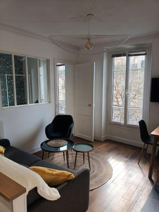 a living room with a couch and two tables at Très Parisien et ensoleillé in Paris