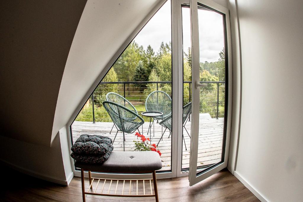 Cette chambre dispose d'une grande fenêtre avec une table et des chaises. dans l'établissement Vakaras cozy apartment in the guest house with the terrace and the stunning view to the river side, à Birštonas