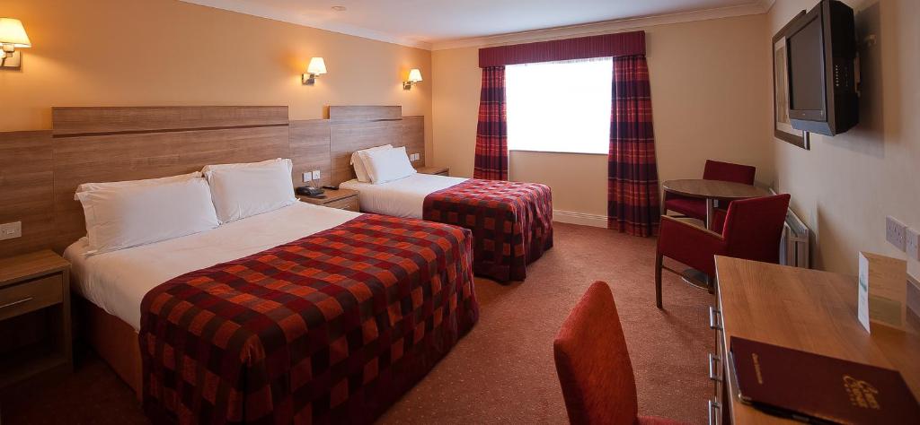 a hotel room with two beds and a television at Corr's Corner Hotel in Newtownabbey