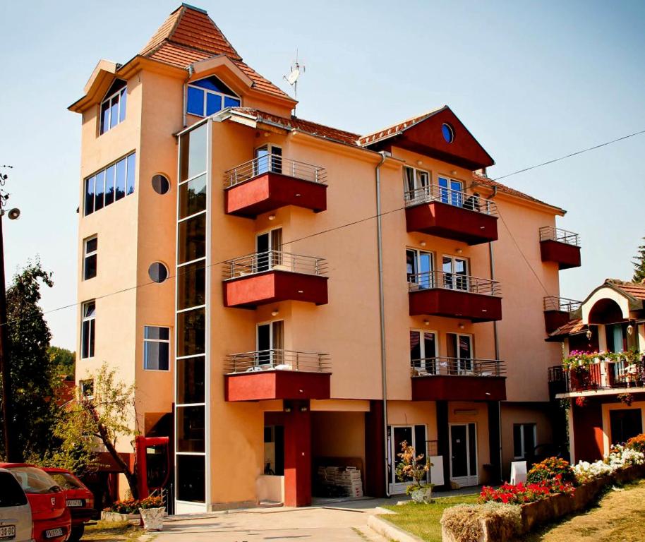 a large building with red balconies on a street at Spa & wellness Villa Garetov Konak in Prolomska Banja