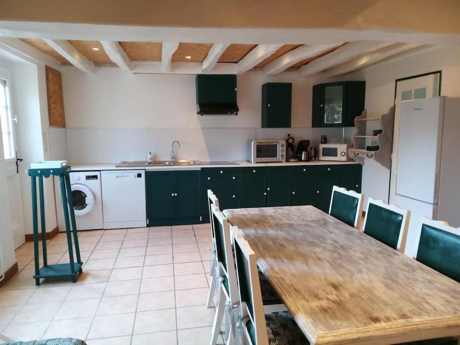 une cuisine avec une table en bois et des armoires vertes dans l'établissement Maison à Mézières-en-Brenne 