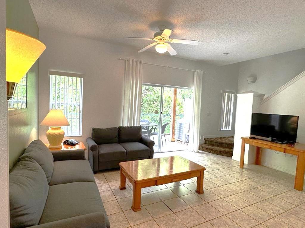 uma sala de estar com um sofá e uma mesa em Cozy Three Bedrooms Townhome at Lake Berkley Resort (1123) em Kissimmee