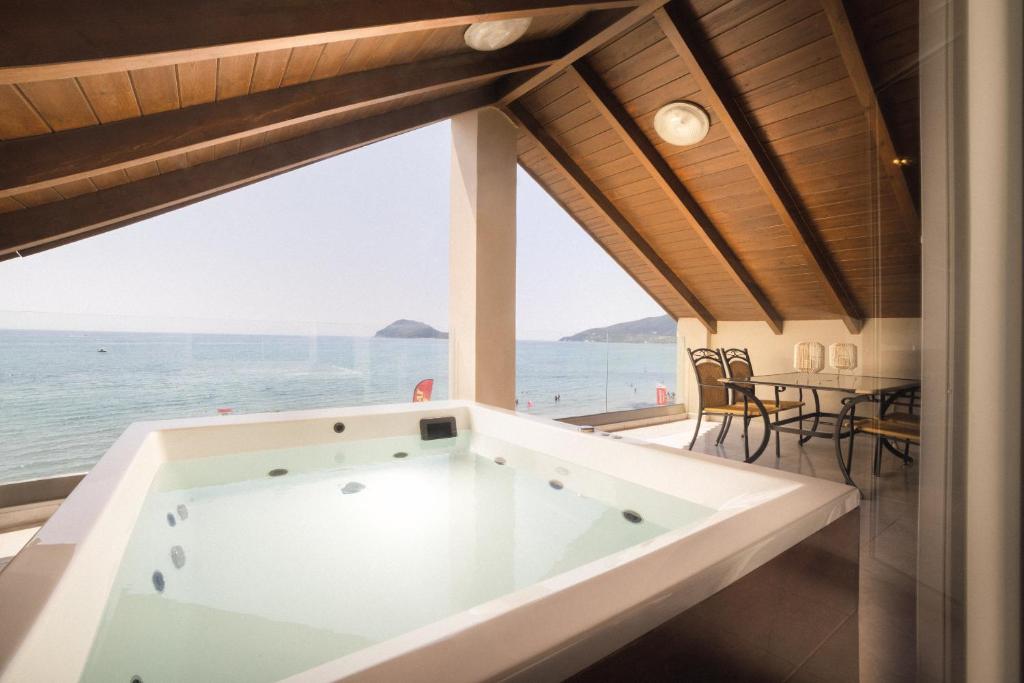 a bath tub in a room with a view of the ocean at George Beachfront Apartments in Lithakia