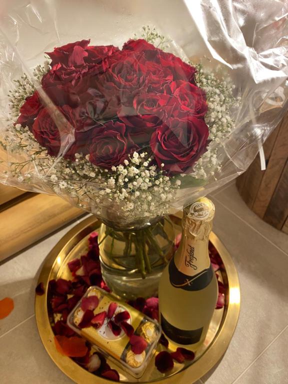 a vase with a bouquet of roses and a bottle of champagne at Love Cottage mit Whirlpool in Hagen