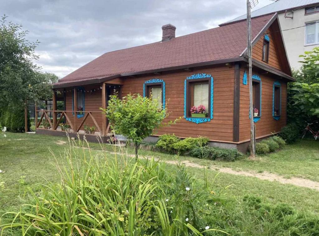 Casa de madera con ventanas azules y patio en Domek na Podlasiu, en Dubicze Cerkiewne