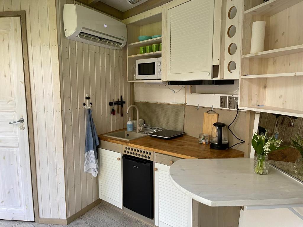 una pequeña cocina con armarios blancos y lavavajillas negro en Mugavustega majake mereäärses männikus., en Lohusalu