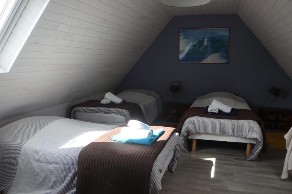 een zolderkamer met 3 bedden en een stoel bij Maison de vacances avec jardin clos à 300m de la mer in Pouldreuzic