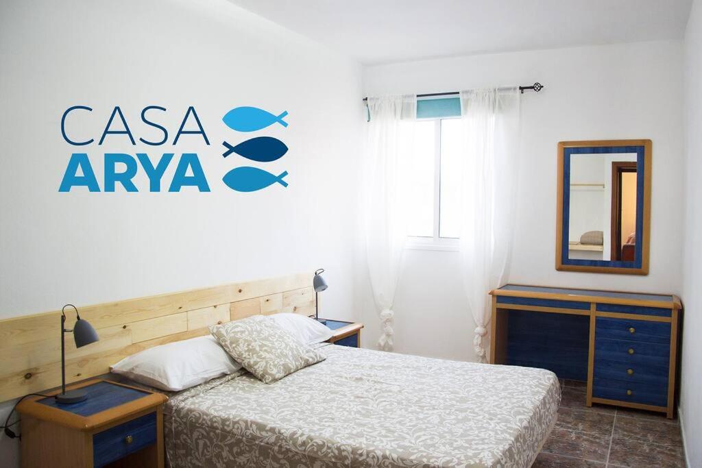 a bedroom with a bed and a fish sign on the wall at Casa Arya in Cotillo