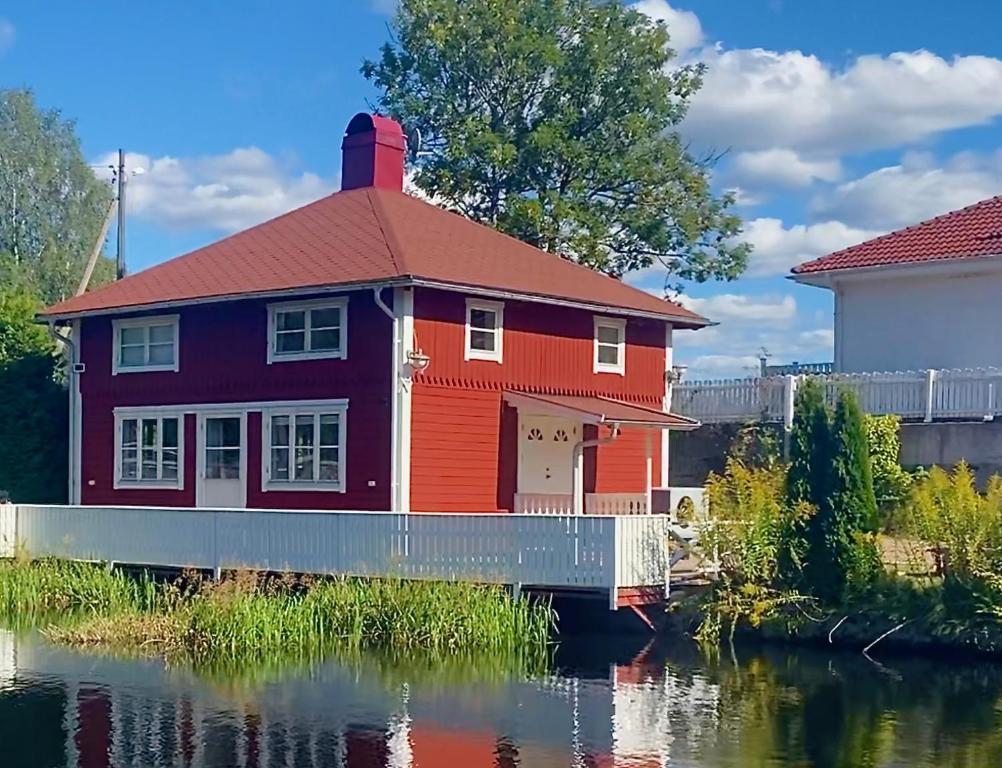 una casa roja en el agua junto a un río en Lovely Waterfront Cottage near Karlshamn en Asarum