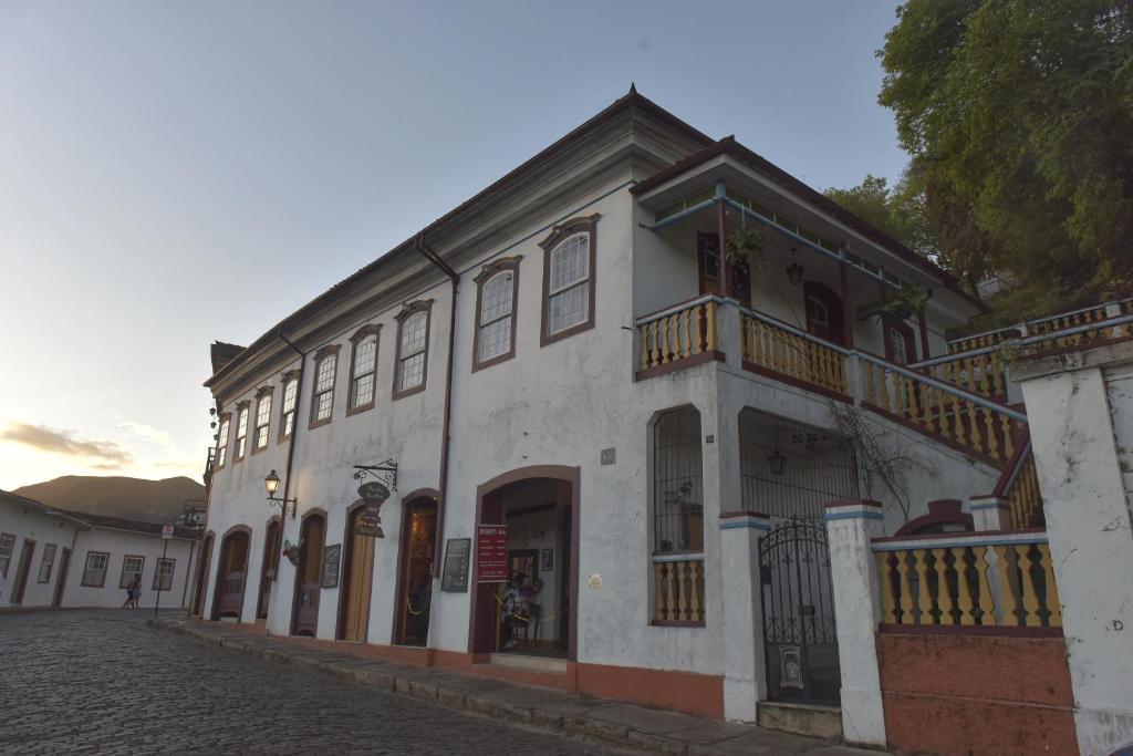 biały budynek z balkonem przy ulicy w obiekcie Casa do Chá Ouro Preto w mieście Ouro Preto