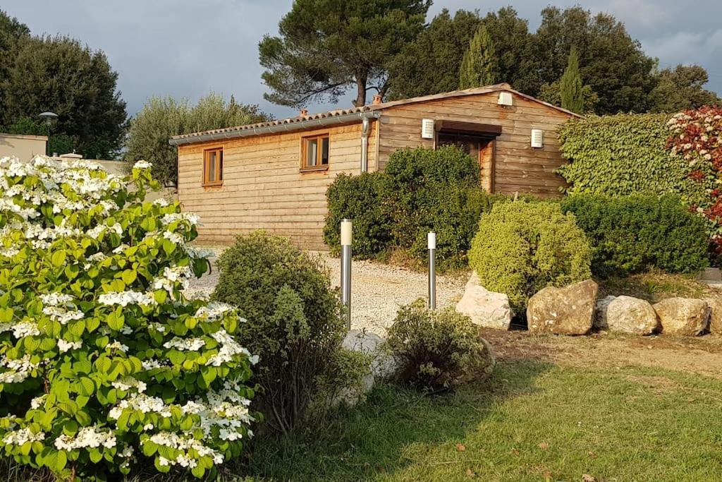 a wooden house with a bunch of bushes and flowers at Chalet de charme climatisé sur la route du Ventoux in Carpentras