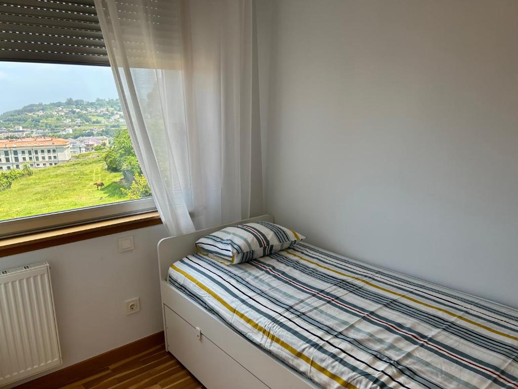 Bett mit Kissen in einem Zimmer mit Fenster in der Unterkunft Playa Miño in Miño