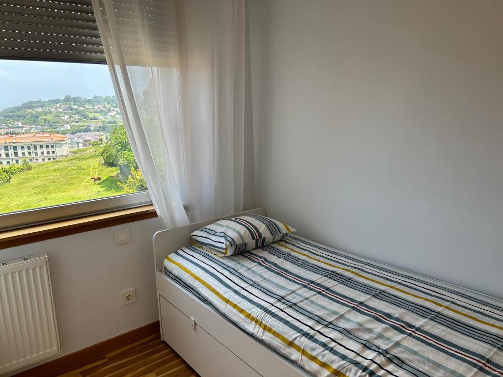 a bed with a pillow in a room with a window at Playa Miño in Miño