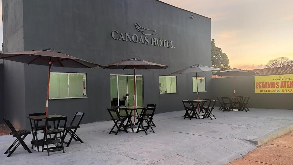 un grupo de mesas y sillas con sombrillas fuera de un edificio en Canoas Hotel, en Três Lagoas