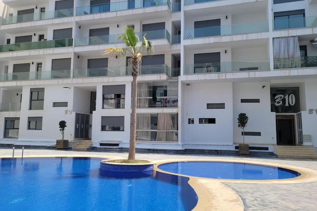 un hôtel avec un palmier en face d'un bâtiment dans l'établissement Luxurious 3BR 1,5Bath flat near the beach, à Agadir