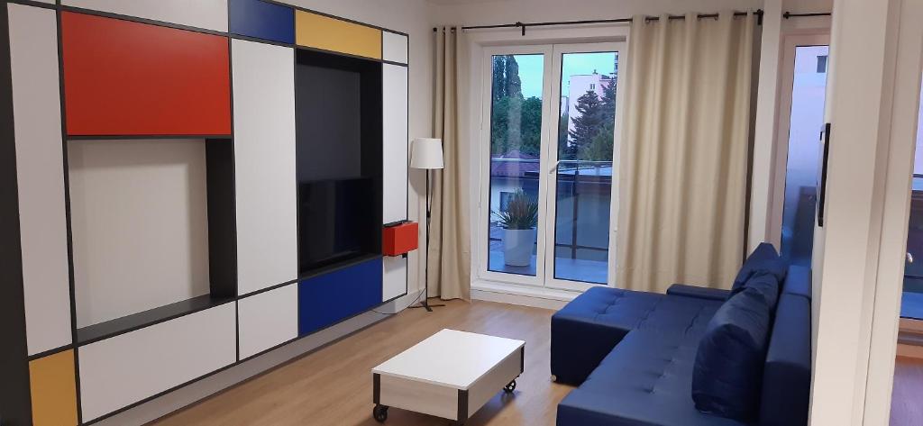 a living room with a blue couch and a tv at Apartament MONDRIAN in Płock