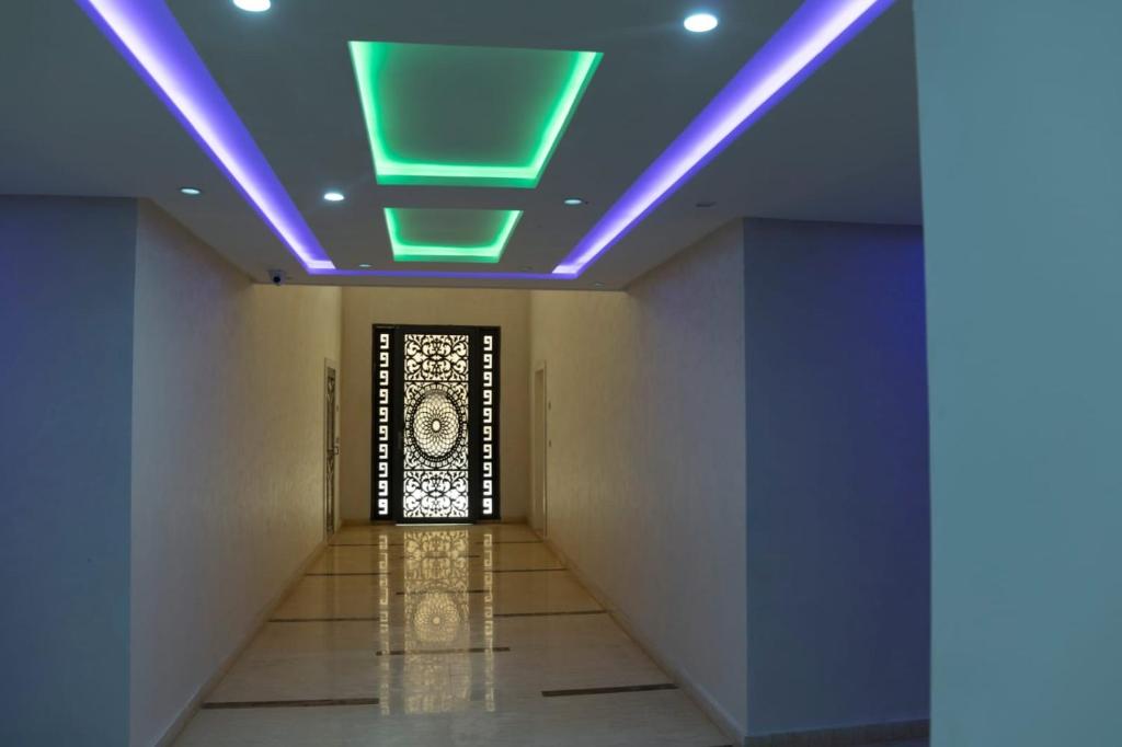 納祖爾的住宿－A&R Apartment Nador Jadid Hay Al Matar ,Klimatisiert,Air-Conditioned，一条带绿色和紫色灯光天花板的走廊