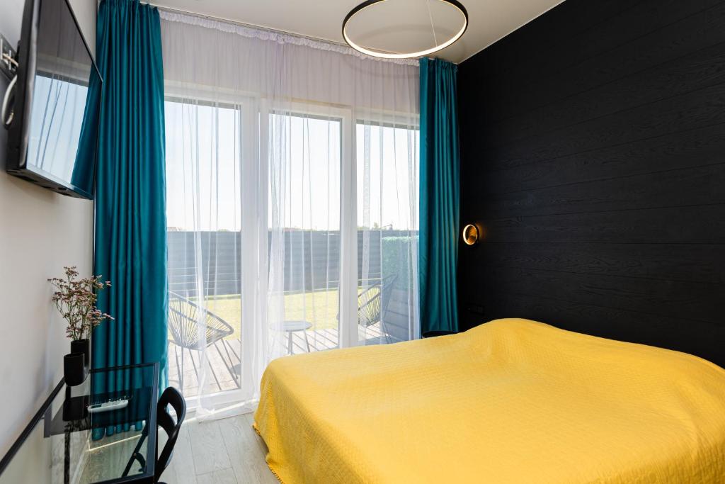 a bedroom with a yellow bed and a large window at 2NIGHT in Šventoji in Palanga