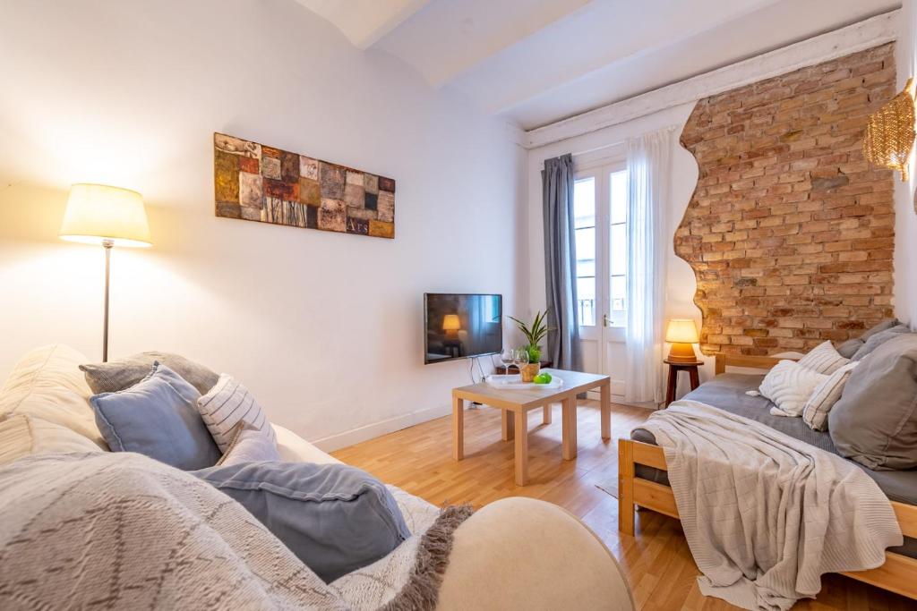 ein Wohnzimmer mit Sofa und Ziegelwand in der Unterkunft Acogedor apartamento en Serrallo in Tarragona