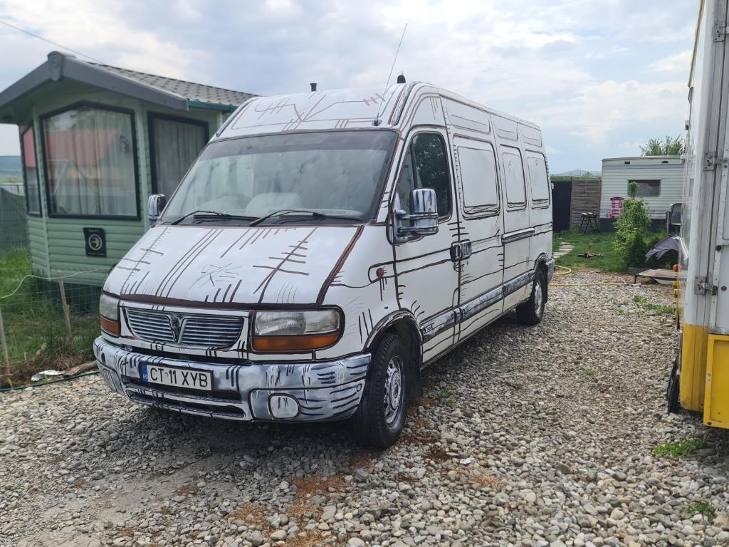 a white van parked on gravel next to a trailer at Camper Niklas in Vama Veche