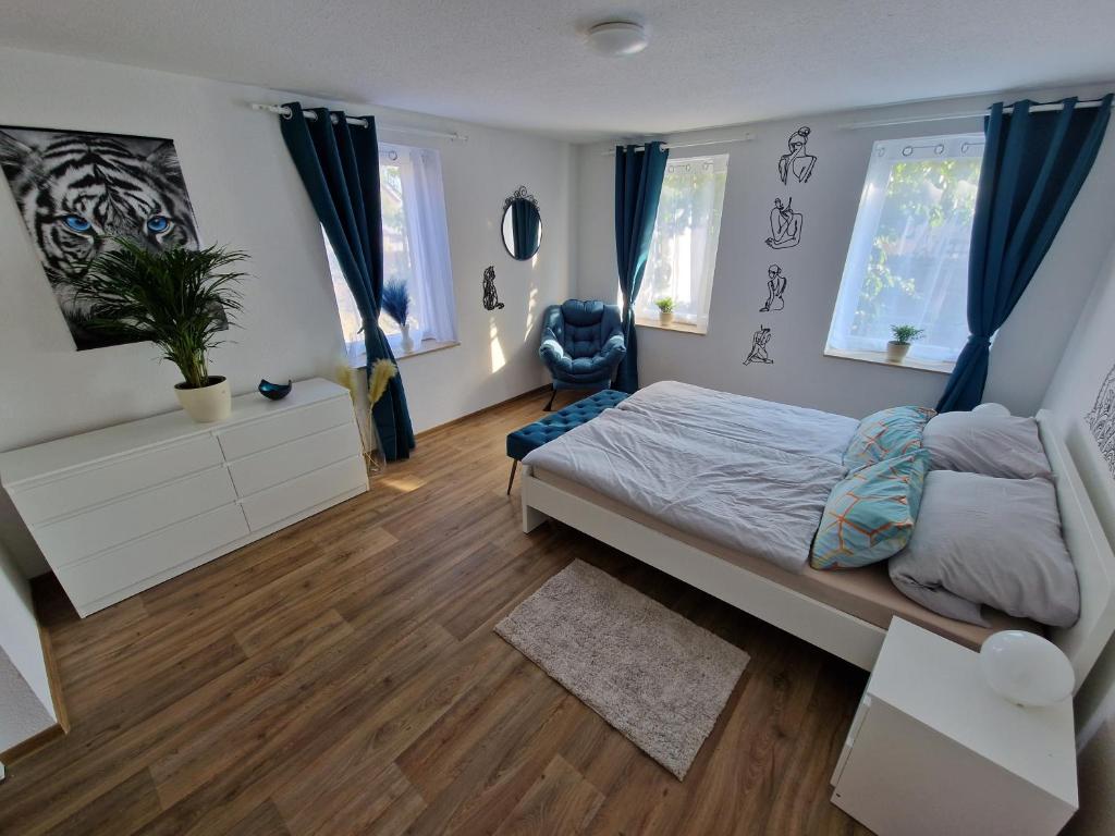 a bedroom with a bed with blue curtains and wooden floors at Ferienhaus Jena - Teamwork Holiday House 