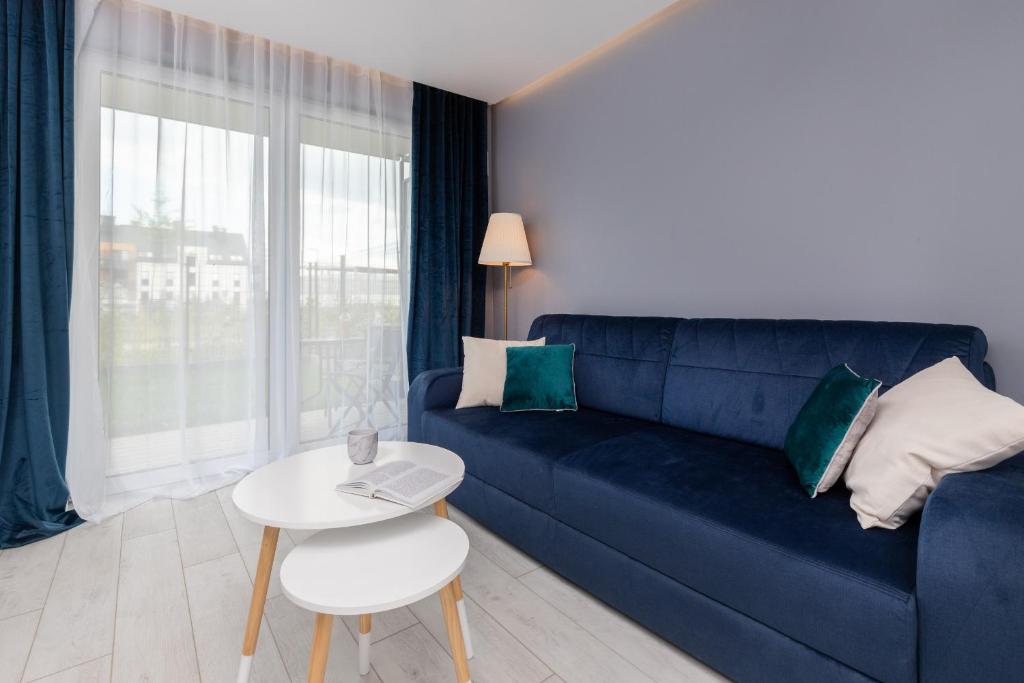Stunning Apartment Hokejowa with Terrace & Parking by Renters في غدانسك: غرفة معيشة مع أريكة زرقاء وطاولة