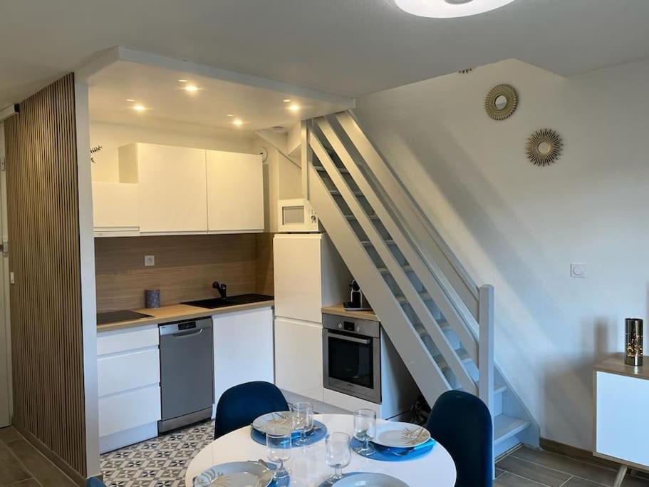 uma cozinha com uma mesa e cadeiras e uma escadaria em Charmant Duplex, 300 m de la mer em Courseulles-sur-Mer