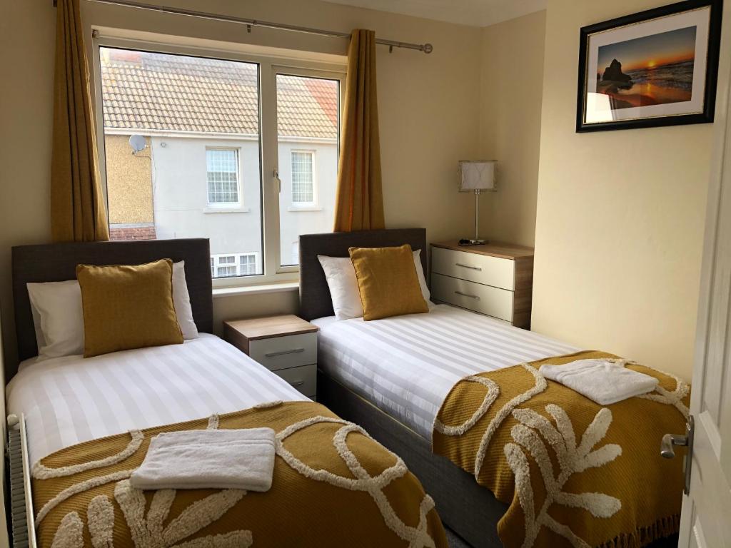 2 camas en una habitación con ventana en Edinburgh Street Home - Beautiful House with Free Parking and Wifi, Equipped with comfy furnitures, en Swindon