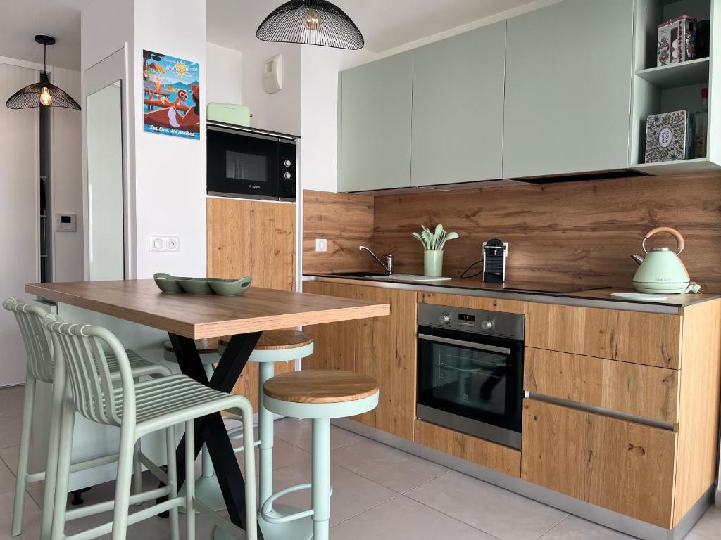 una cocina con armarios blancos y una mesa y sillas de madera. en ENTRE NOUS CITY, en Annecy