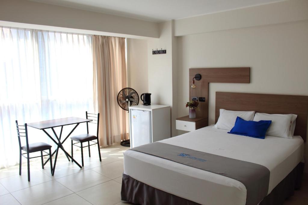 1 dormitorio con 1 cama y 1 mesa con sillas en Hotel Luxotel Chincha, en Chincha Alta