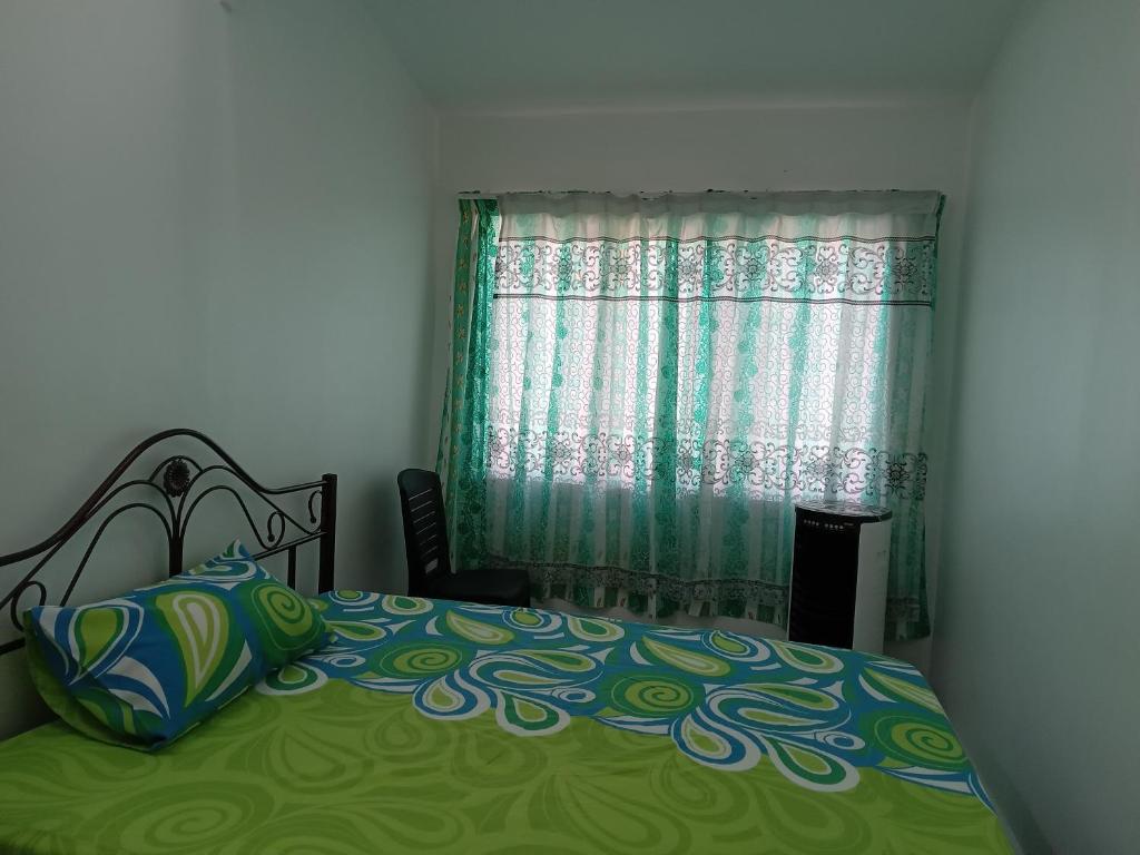 een slaapkamer met een bed met een groene deken en een raam bij Narayana Illam in Nilai