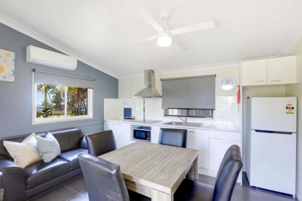 a living room with a table and a couch and a kitchen at Reflections Nambucca Heads - Holiday Park in Nambucca Heads