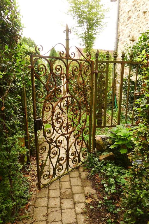 une porte menant à un jardin avec une passerelle en pierre dans l'établissement La Cage aux Oiseaux, à La Lande-de-Goult