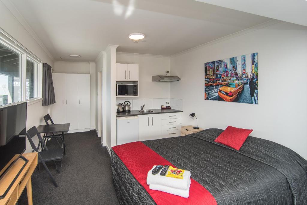a bedroom with a large bed and a kitchen at The Hibernian Studio Apartments - 4 Latter Street in Timaru