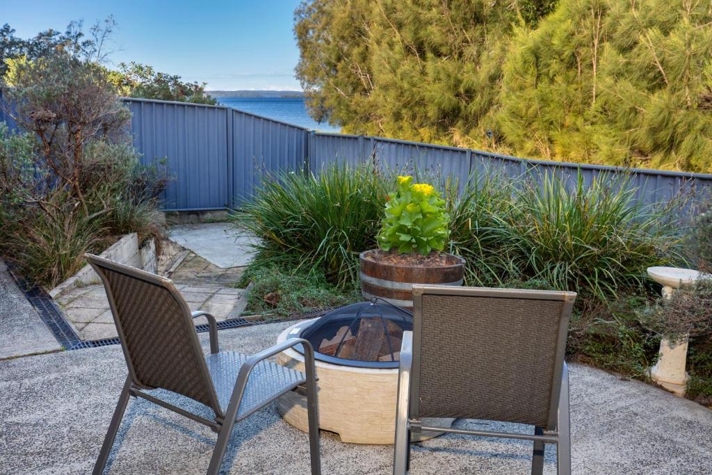 a patio with two chairs and a table with a potted plant at Reflections Pet Friendly Waterfront in Basin View