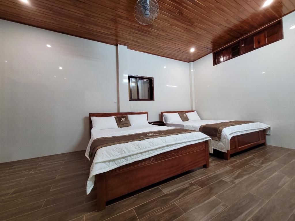 two beds in a room with wooden ceilings at Ngọc Anh homestay in Thôn Kim Long (1)