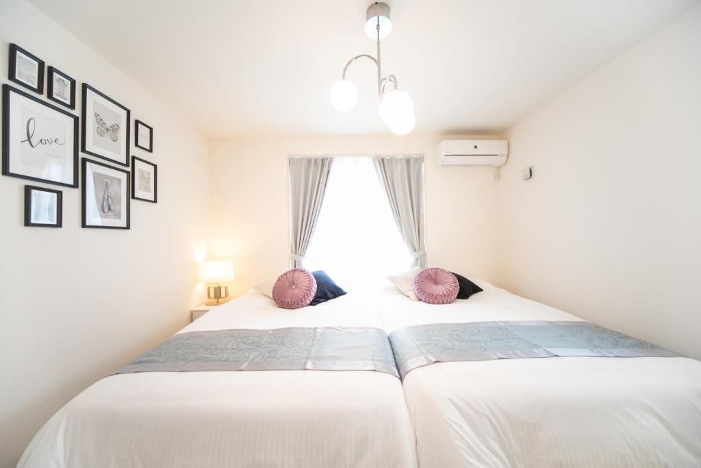 1 dormitorio con 1 cama con sábanas blancas y almohadas rosas en Nagashima Riverside Condominium, en Hakuro