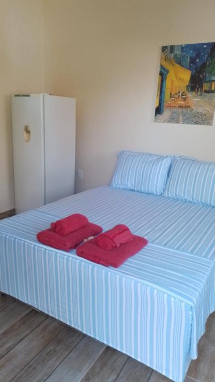 a blue and white bed with red towels on it at SUITE ACONCHEGANTE 02 in Saquarema