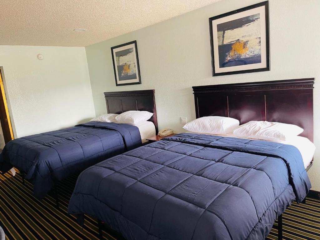 Dos camas en una habitación de hotel con colchas azules en Executive Inn, en Muskogee