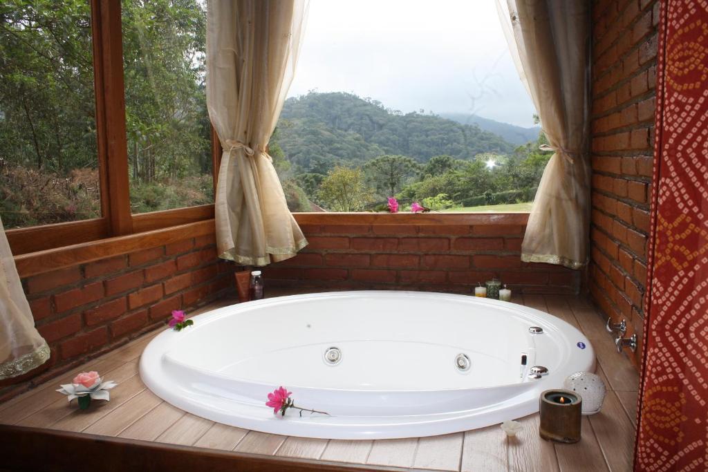 bañera en una habitación con ventana en Chalé Samasati, en Visconde De Maua