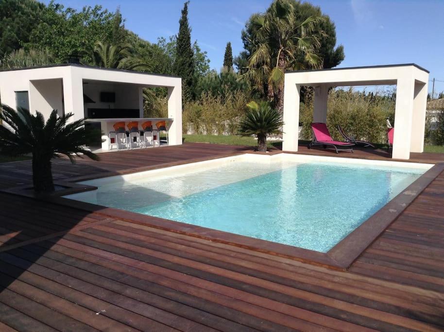 une piscine avec une terrasse en bois à côté d'une maison dans l'établissement VILLA GRAND STANDING SPA PISCINE, au Cap d'Agde