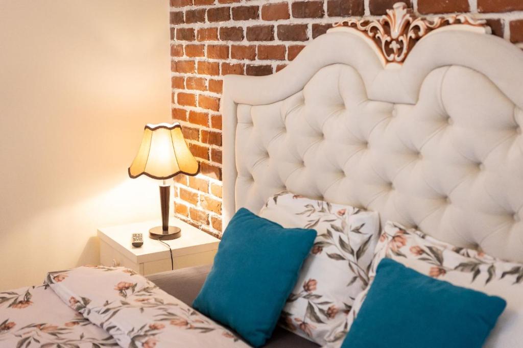 a bedroom with a bed with blue pillows and a brick wall at IZZY'S HIDDEN APARTMENT in Braşov