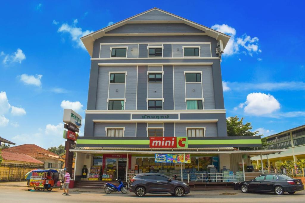 um edifício alto com carros estacionados em frente em Chonlapruk Lakeside Hotel em Ban Si Than